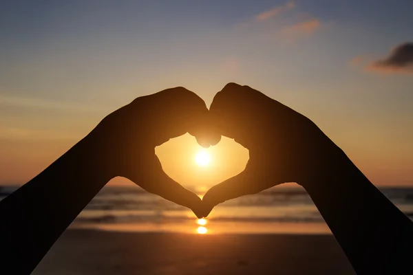 Silhouette delle mani nel simbolo del cuore intorno al sole — Foto Stock