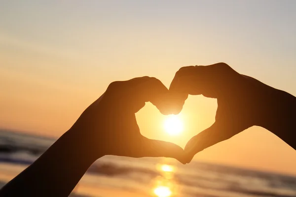 Silhouette delle mani nel simbolo del cuore intorno al sole — Foto Stock