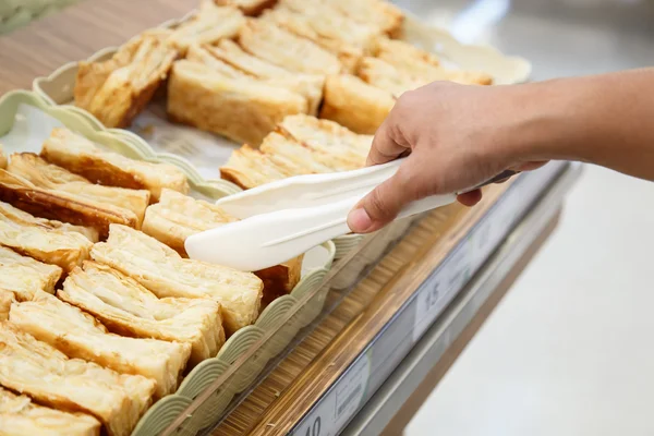 Hand holding Serving kitchen tongs in bakery shop