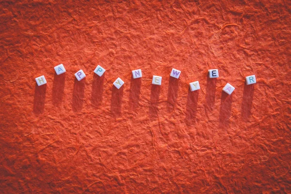 Happy New Year written in letter beads on mulberry paper backgro Royalty Free Stock Images