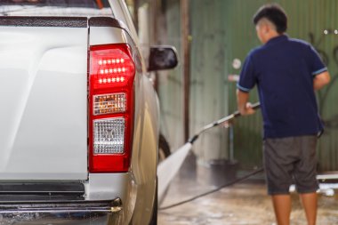 Bir araba yıkama için yıkayıcı basınç kullanan adam, bulanıklık