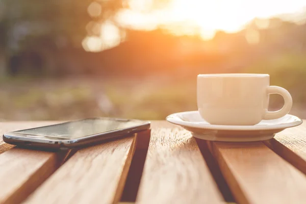 Una taza de café y teléfono inteligente sobre la mesa — Foto de Stock