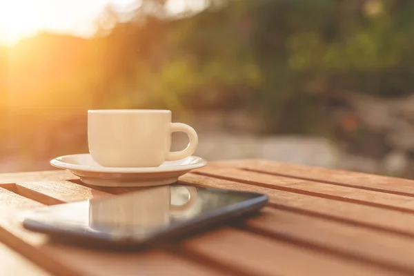 Filiżankę kawy i smartphone na stole — Zdjęcie stockowe