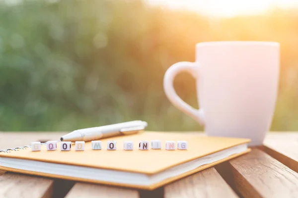 God morgon skrivet i brevet pärlor och en kaffekopp på bord — Stockfoto