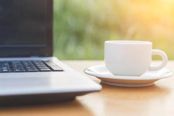 Una taza de café y un portátil en la mesa — Foto de Stock