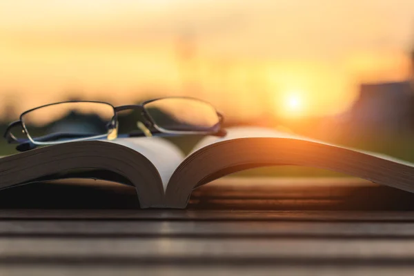 Close up book and glasses on table in sunset time — Stock Photo, Image