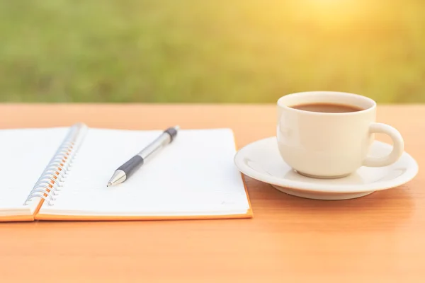 Nära håll kaffekopp och anteckningsboken på bordet — Stockfoto