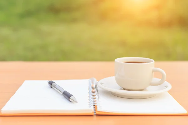 Cierre la taza de café y el cuaderno en la mesa —  Fotos de Stock