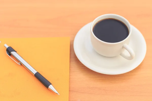 Nära håll kaffekopp och anteckningsboken på bordet — Stockfoto