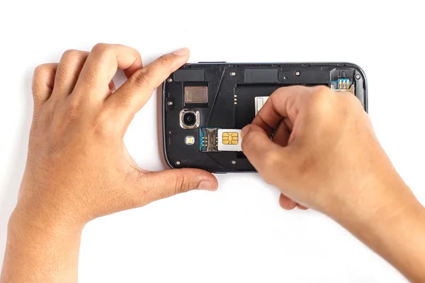 Mano celebración de la tarjeta SIM y poner en el teléfono inteligente aislado en blanco — Foto de Stock