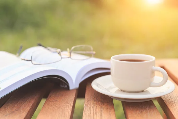 Zblízka šálek kávy a kniha na stole ráno — Stock fotografie
