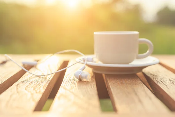 ปิดหูฟังและถ้วยกาแฟบนโต๊ะในตอนเช้า — ภาพถ่ายสต็อก