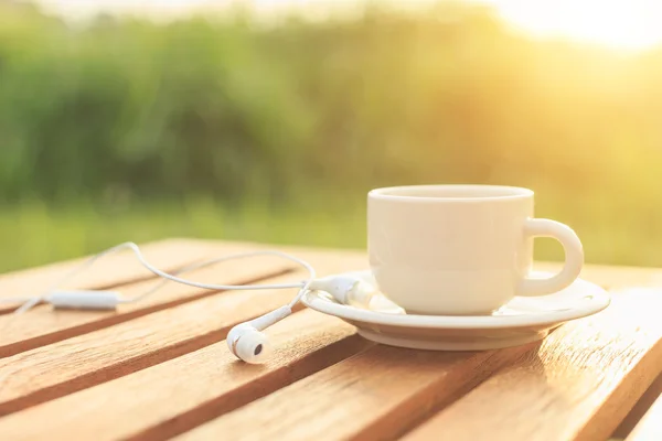 Κοντινό πλάνο φλιτζάνι καφέ και ακουστικά στο τραπέζι το πρωί — Φωτογραφία Αρχείου