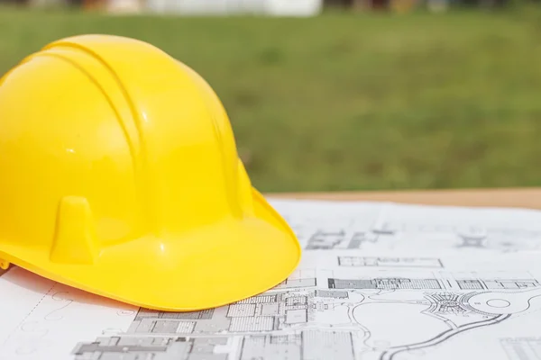 Close up Yellow safety helmet and floor plan drawings on the tab