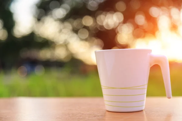 Cangkir kopi di atas meja saat matahari terbenam — Stok Foto