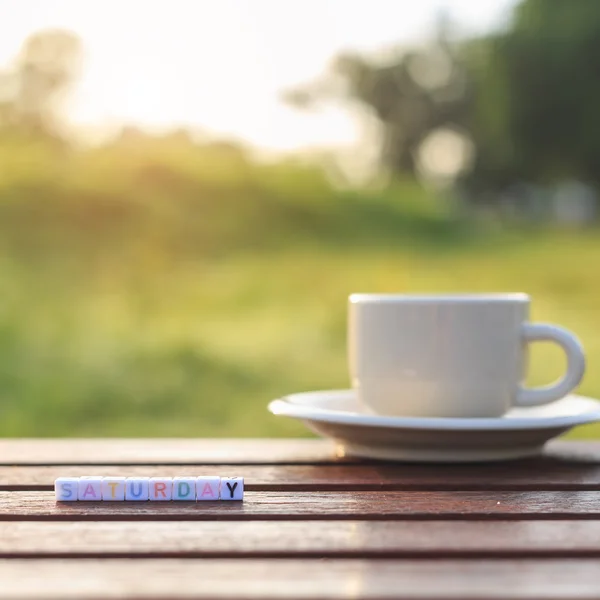 Lördag skrivet i brevet pärlor och en kaffekopp på tabell — Stockfoto