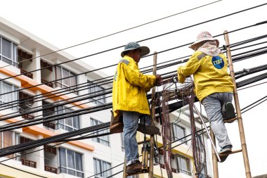 İki erkek işçi bambu merdiven üzerinde 20 Ağustos 2014 Phuket Tayland telefon hattı community yakınındaki onarıyor.