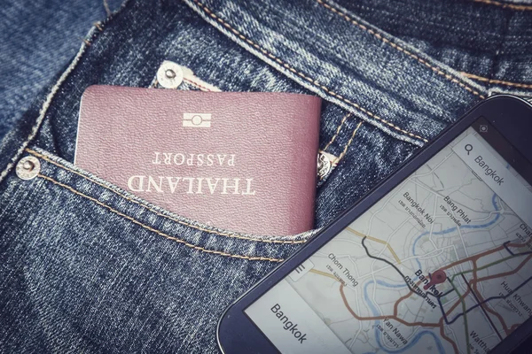 Pasaporte en bolsillo vaquero y mapa en smartphone —  Fotos de Stock