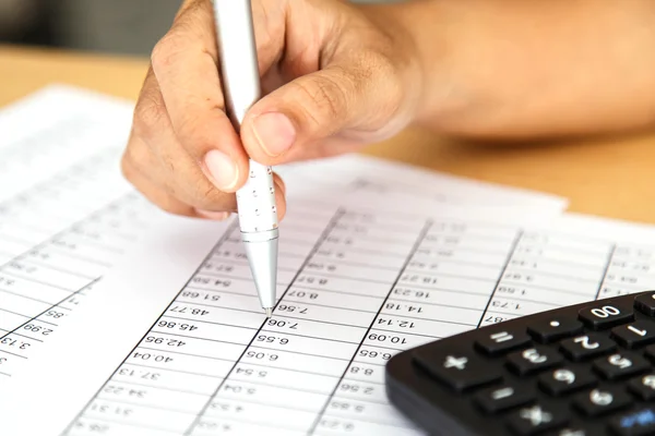 Close up woman hand holding pen on spreadsheet — Stock Photo, Image