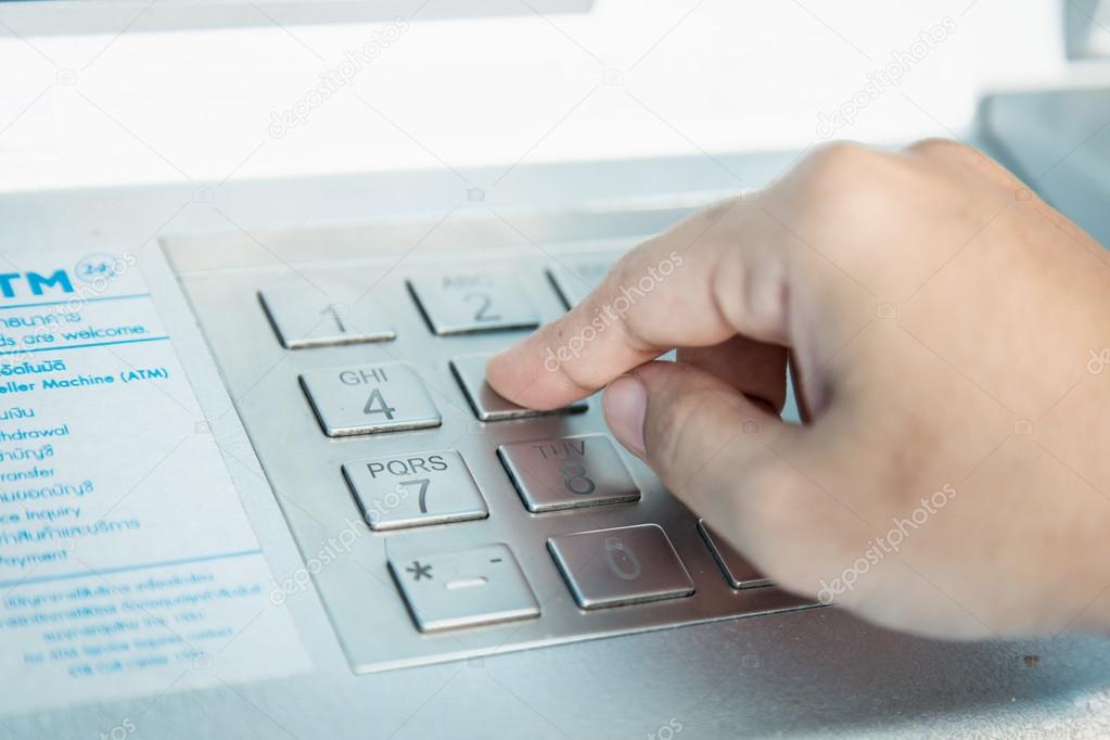 Close up of hand entering PIN pass code on ATM bank machine keyp