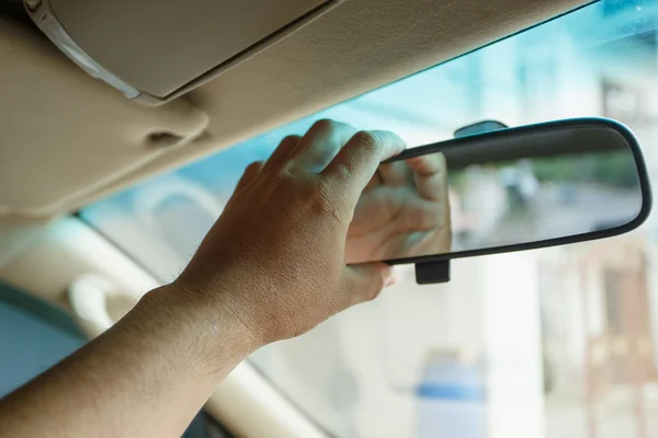 A hand holding mirror  in the car