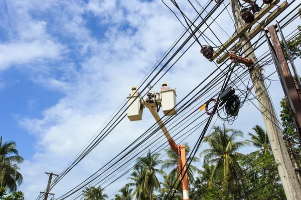 Electrician stays on the tower pole and repairs a wire of the po — Stock Photo, Image