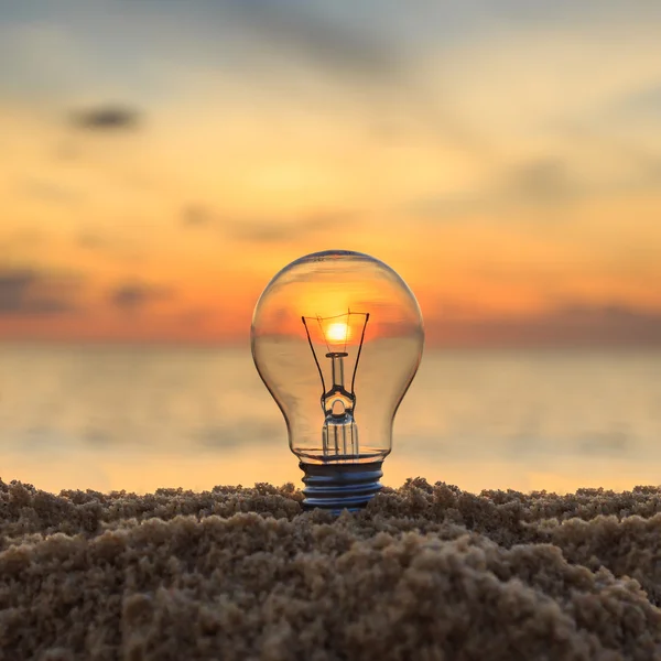 Close up light bulb on sunset beach — Stock Photo, Image
