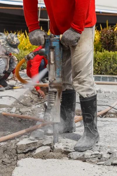 Operaio utilizzando costruzione di perforazione cemento a terra — Foto Stock