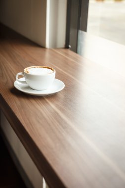 Kahve fincanı ve kitap masanın üstünde.