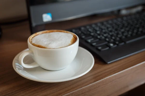 Šálek kávy a počítač na stole — Stock fotografie