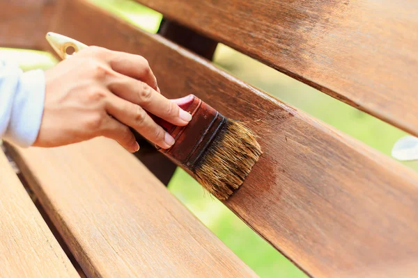 Hand holding brush and paint timber — Stock Photo, Image