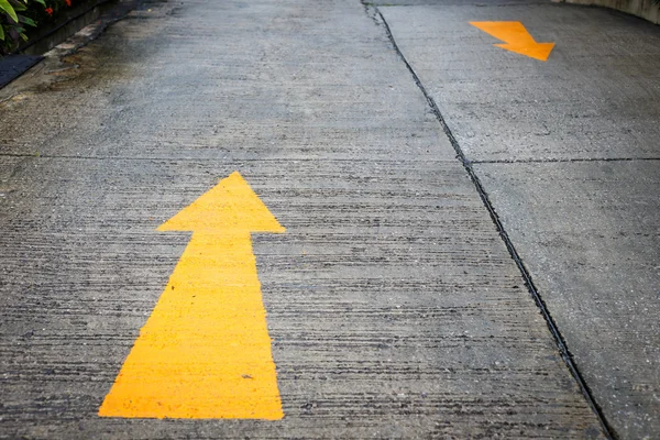 A yellow arrow symbol on a road surface — Stock Photo, Image