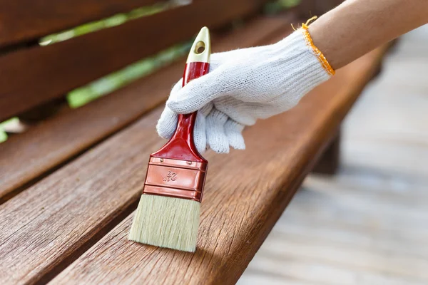 Ręka trzyma pędzel i farby drewna — Zdjęcie stockowe