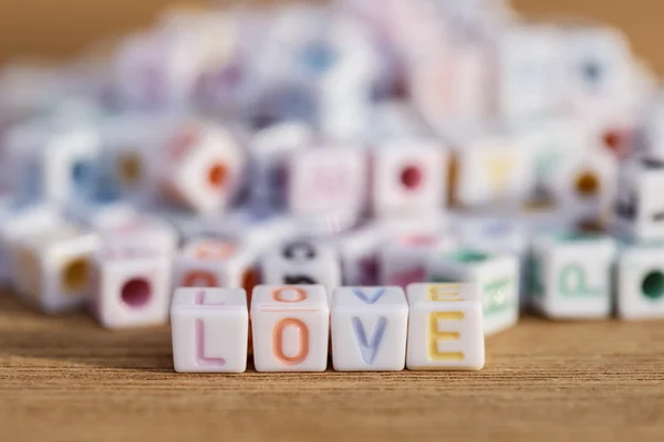 Love written in letter beads on wood background — Stock Photo, Image