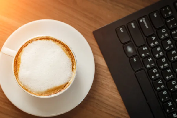 Kaffekop og computer på bordet - Stock-foto