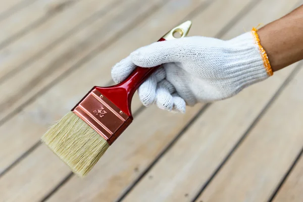 ブラシと塗料の木材を持っている手 — ストック写真