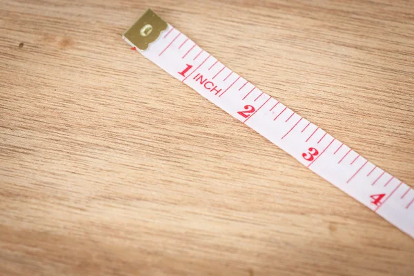 White measure tape on wood texture — Stock Photo, Image