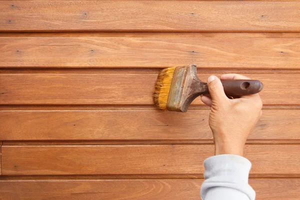 Pincel en mano y pintura en la pared de madera — Foto de Stock