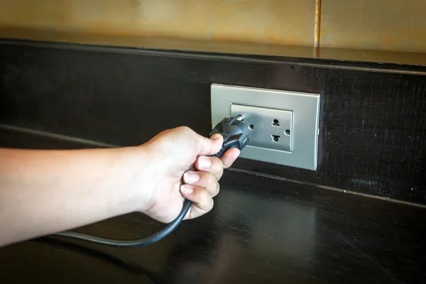 Insertar a mano un enchufe eléctrico en un enchufe de pared . — Foto de Stock
