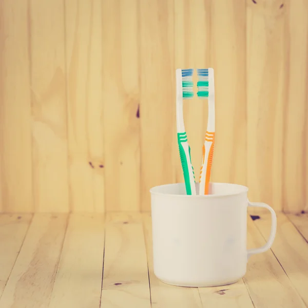 Toothbrushes in cup on wooden table — Stock Photo, Image