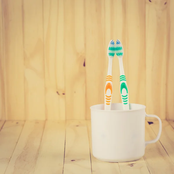 Toothbrushes in cup on wooden table — Stock Photo, Image