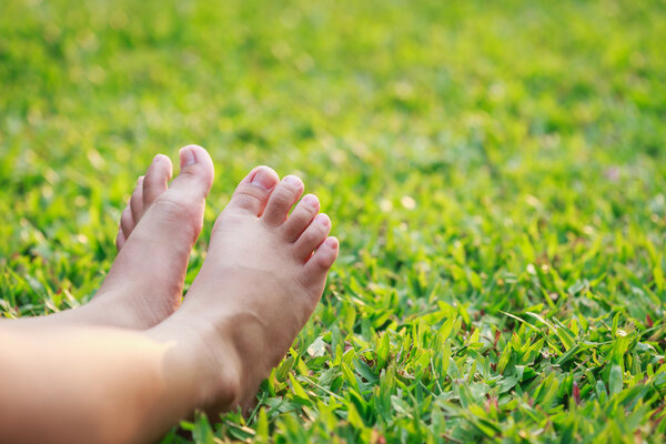 Children feet on green grass