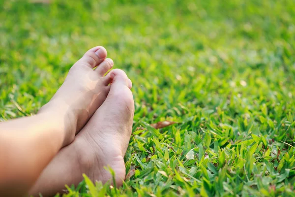 Barn fötter på grönt gräs — Stockfoto