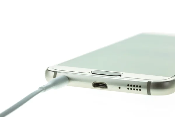 Макросмартфон подключается к наушникам, изолированным на белом — стоковое фото