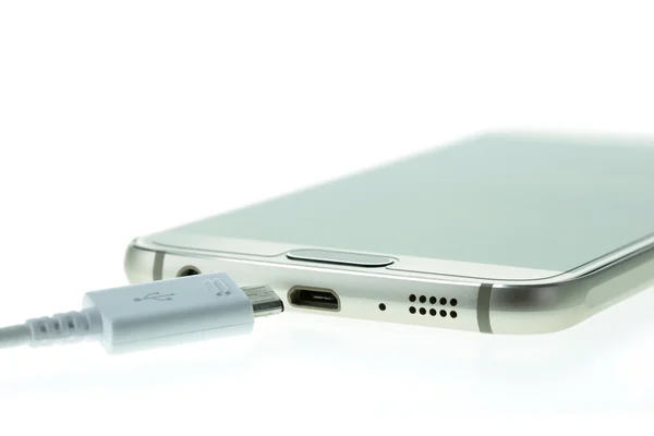 Макросмартфон соединяется с зарядным устройством, изолированным на белом — стоковое фото
