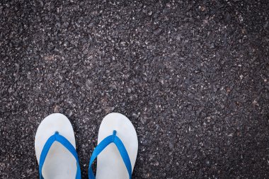 Beyaz plastik flip flop ayakkabı siyah asfalt yolda