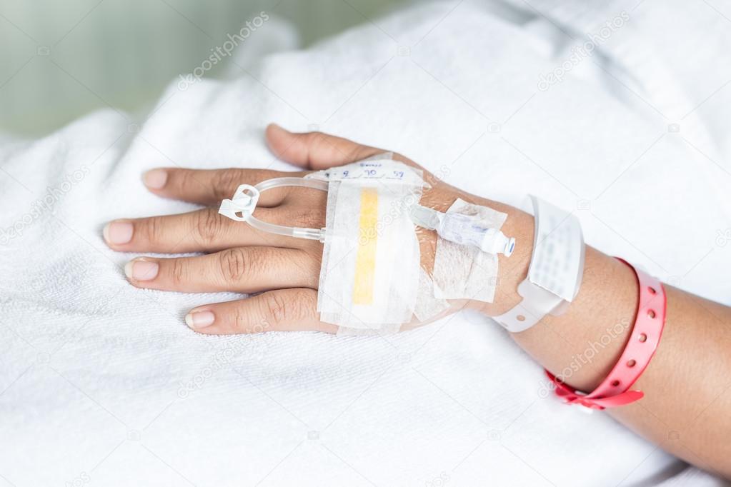 Hand of female patient with IV drip needle piercing in hospital