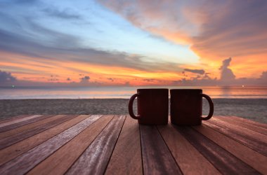 kahve fincanı gündoğumu veya günbatımı Plajı'nda ahşap masa üzerinde