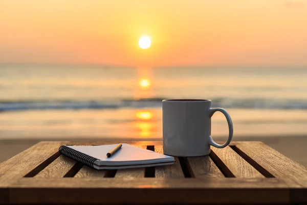 Φλιτζάνι καφέ στο ξύλινο τραπέζι στο ηλιοβασίλεμα ή sunrise beach — Φωτογραφία Αρχείου