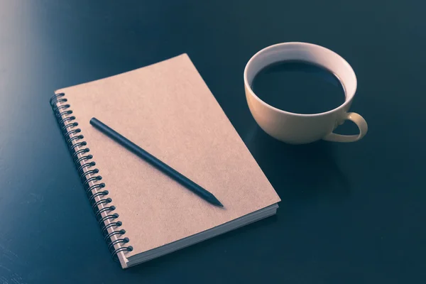 Libro y taza de café sobre mesa de madera negra — Foto de Stock